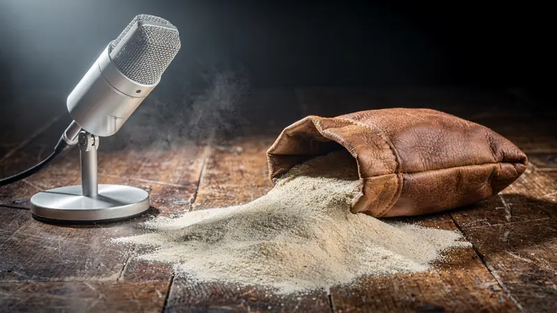 Sac de cuir renversé, farine de maïs répandue sur un plancher de studio, micro sur pied à gauche