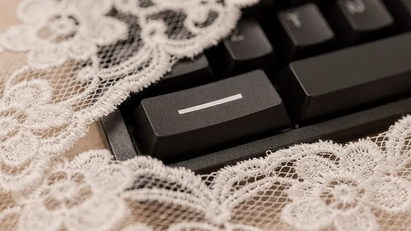 Touche de clavier noire gravée d'un tiret, à demi voilée sous de la dentelle blanche